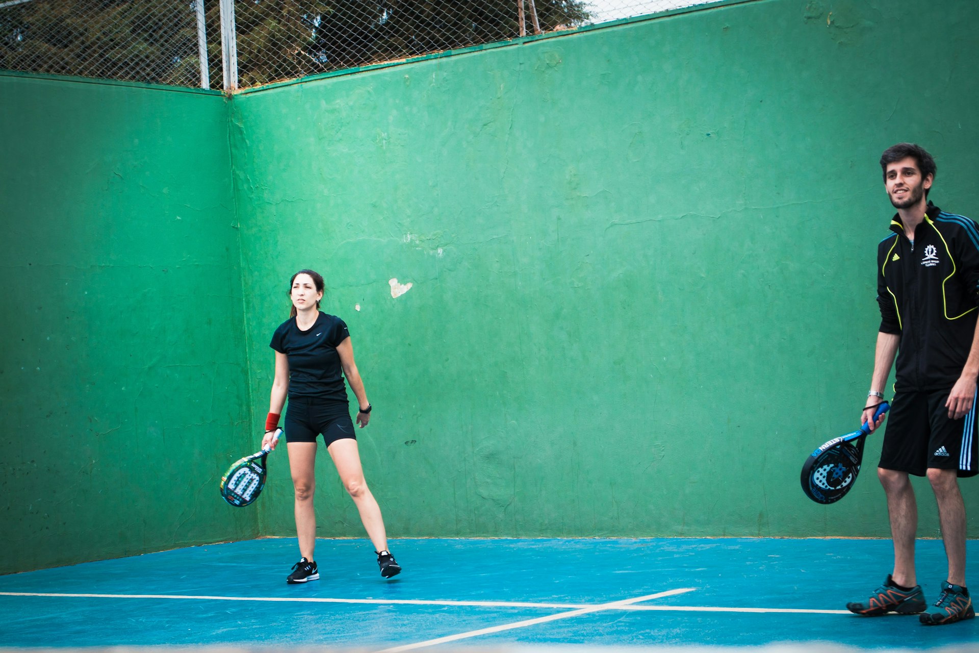 a man and woman standing on a tennis court holding racquets